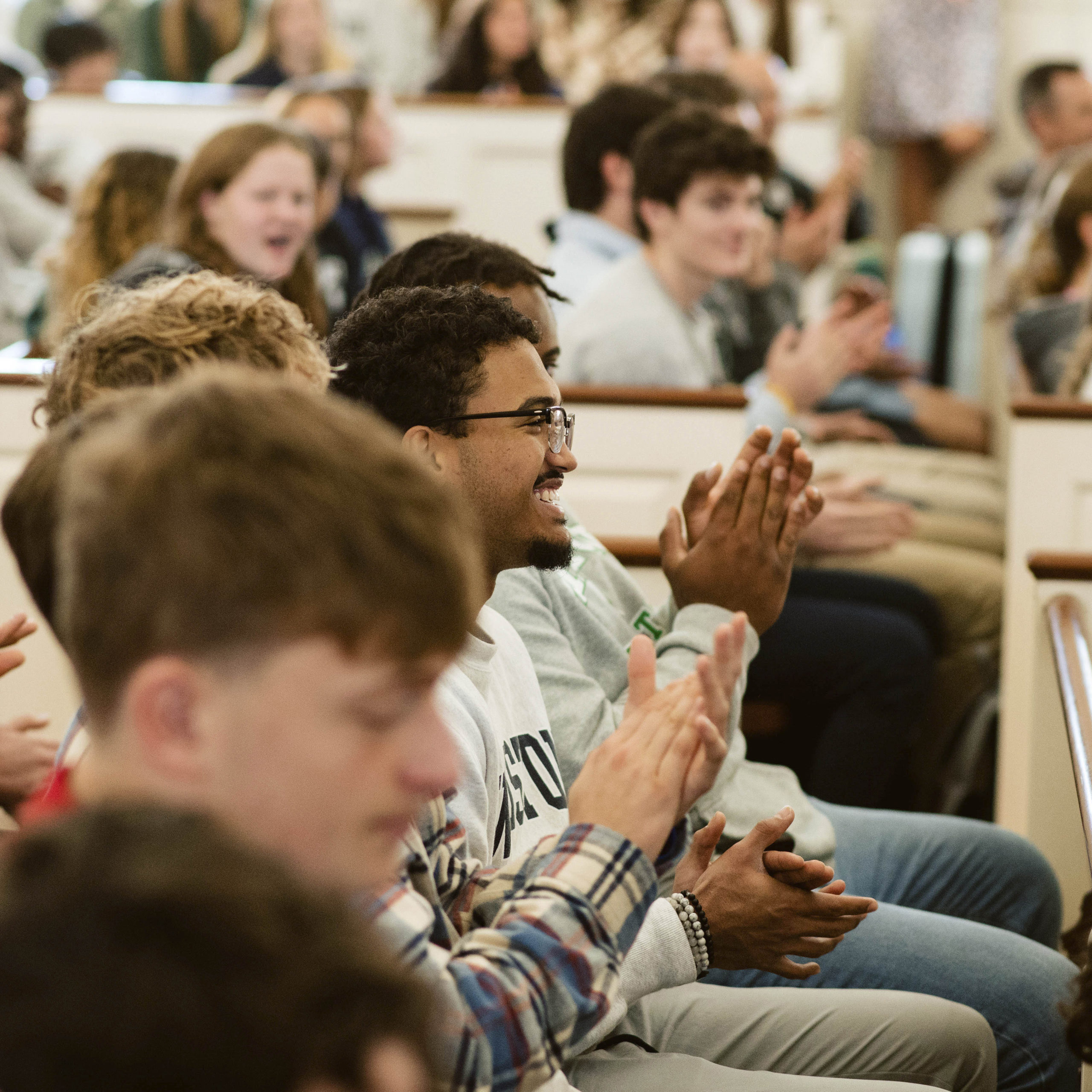 Student laughs as other students clap