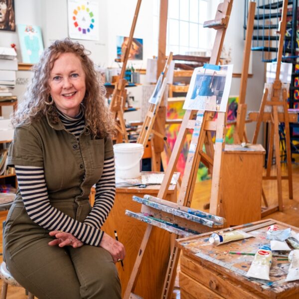 Elizabeth Duffy artist in painting studio sitting on stool