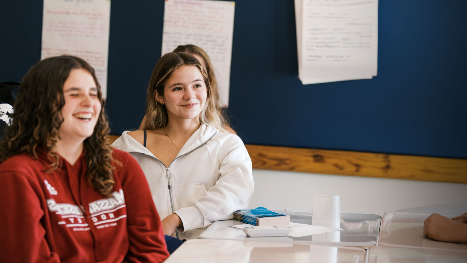 two girls in a classroom, one laughing