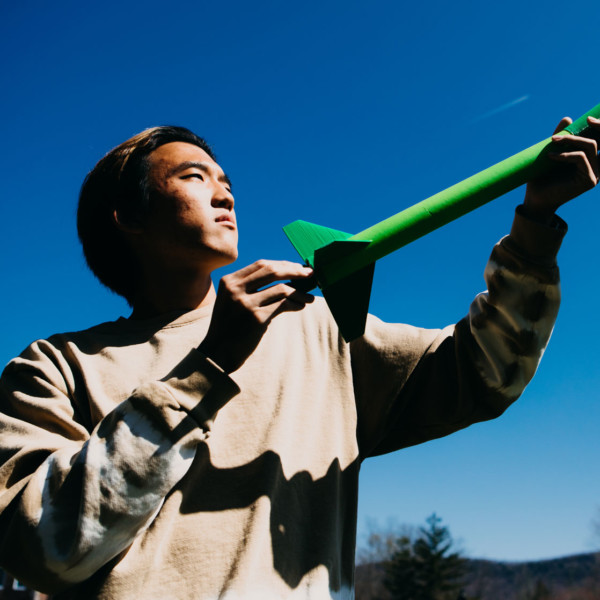 boy with rocket against blue sky and trees