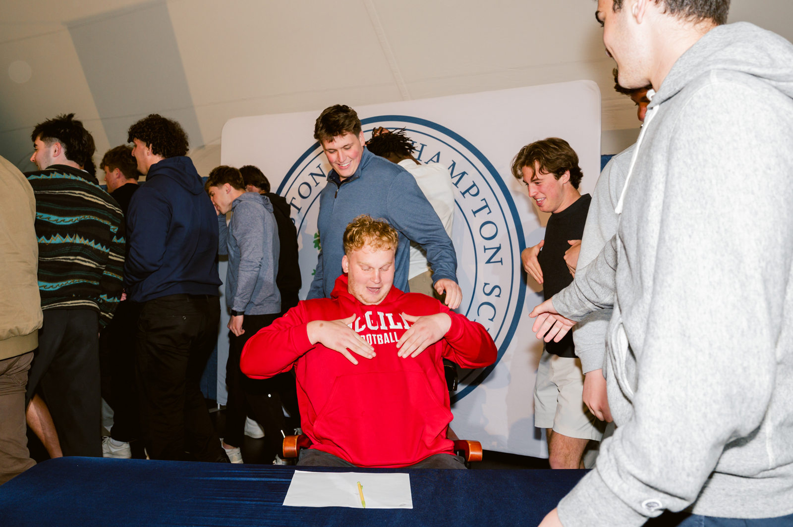 Student in red sweatshirt celebrates with friends