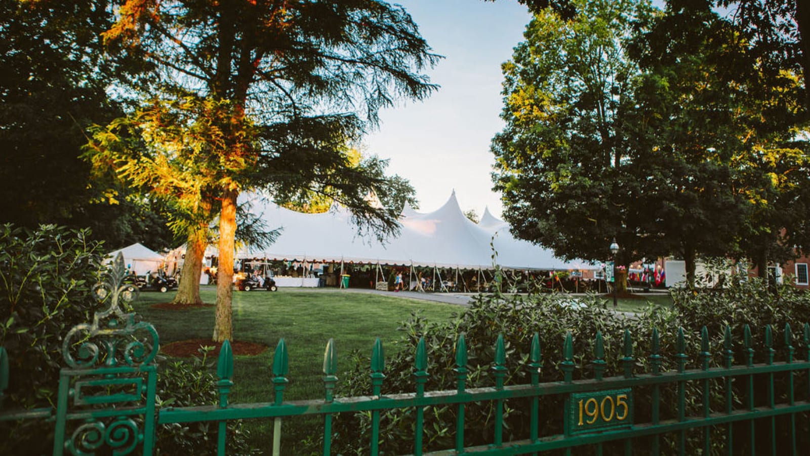 large white tent on lawn with green fence